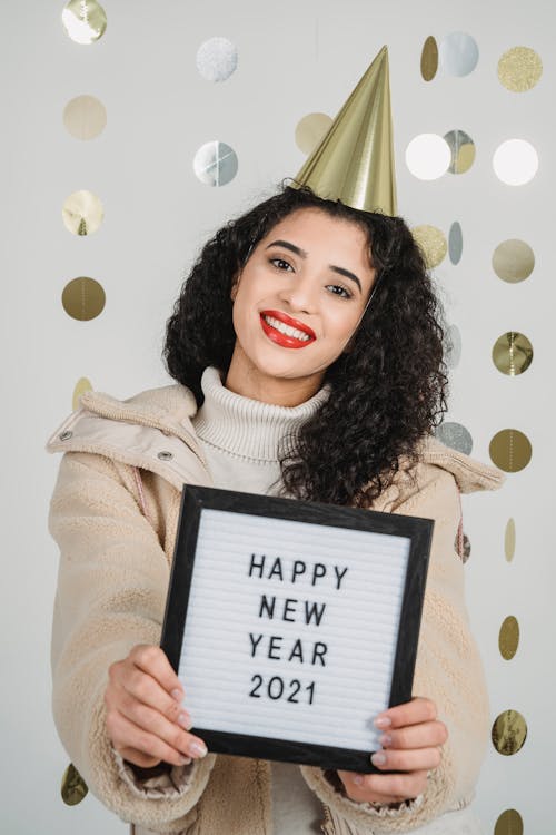 Cheerful ethnic woman demonstrating frame with inscription for New Year