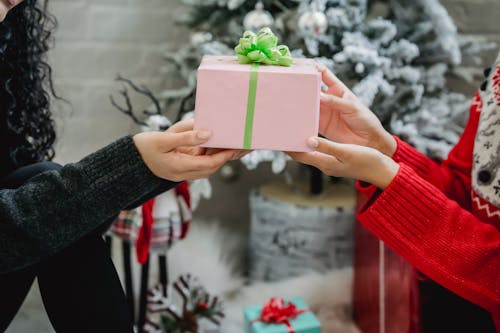 Crop anonymous woman getting present from friend while celebrating New Year together at home