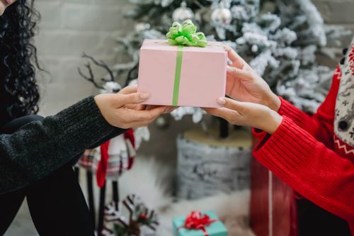 Free Crop anonymous woman getting present from friend while celebrating New Year together at home Stock Photo