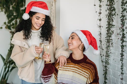 Happy ethnic women celebrating Christmas with champagne