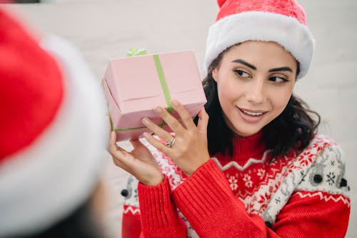 High angle of positive ethnic woman getting present from friend for New Year holiday