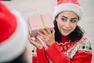 High angle of positive ethnic woman getting present from friend for New Year holiday