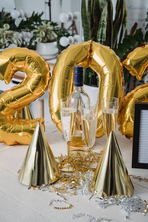 Free New Year decorations placed on table with glass of champagne near cone caps and rain tinsel Stock Photo