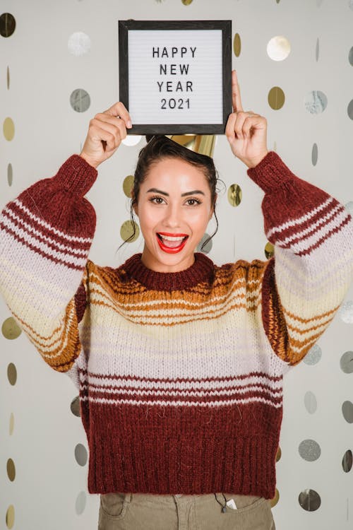 Excited ethnic woman showing frame with congratulation of New Year