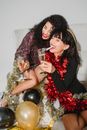 High angle of drunk female friends with champagne in tinsel celebrating New Year and laughing