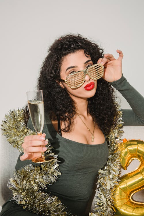 Glamour female with red lips in striped glasses with glass of champagne celebrating New Year
