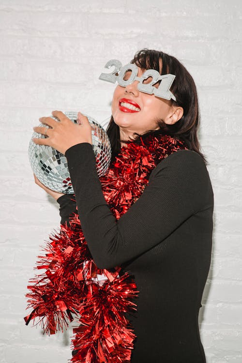 Young woman in red tinsel with sparkling disco ball