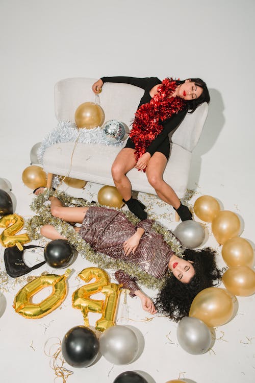 Drunk women in glimmering tinsel among balloons