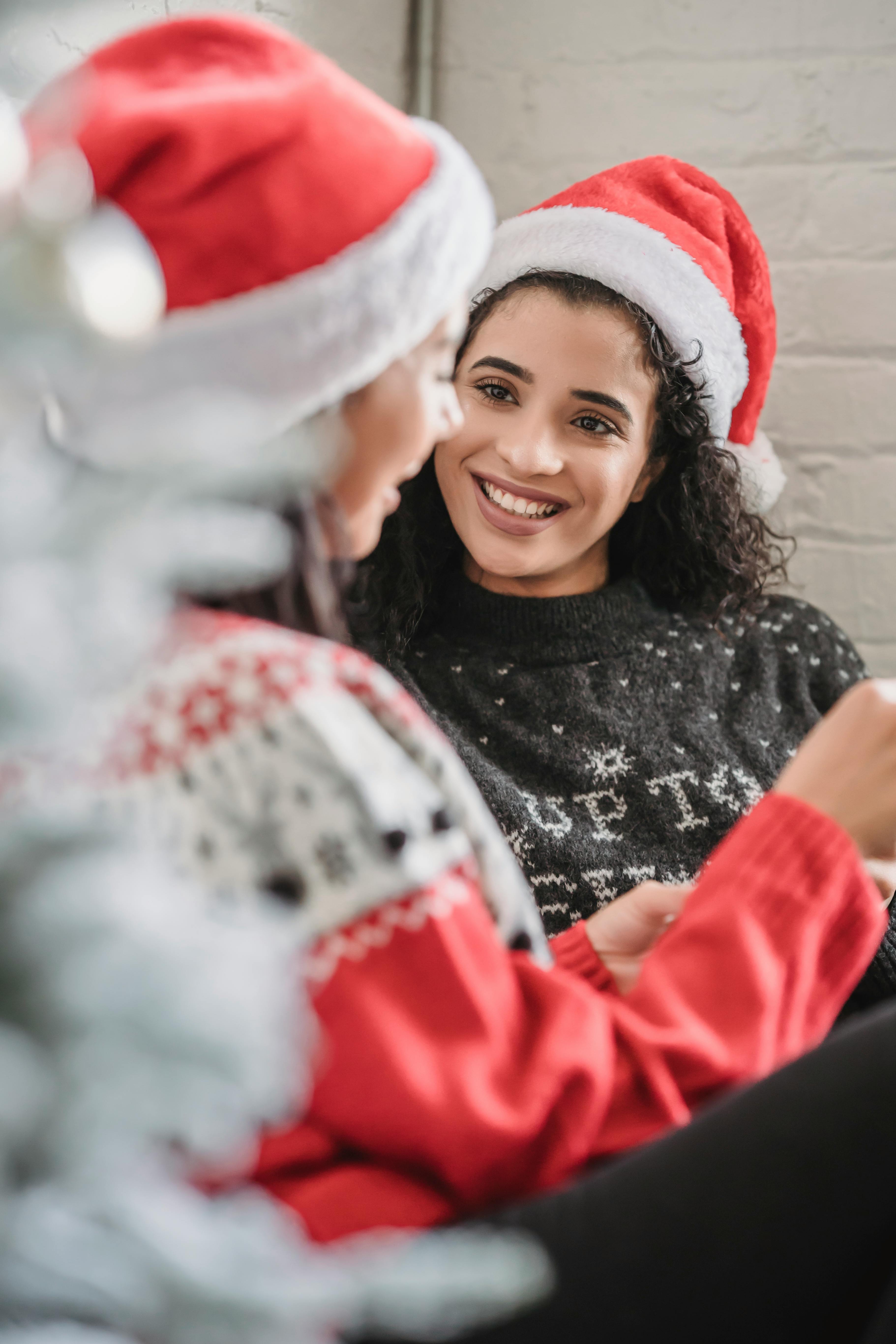 diverse cheerful women in santa hats smiling and talking