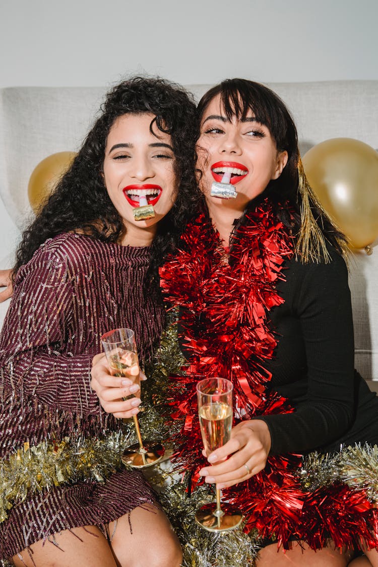 Cheerful Women In Tinsel With Party Whistles Near Balloons