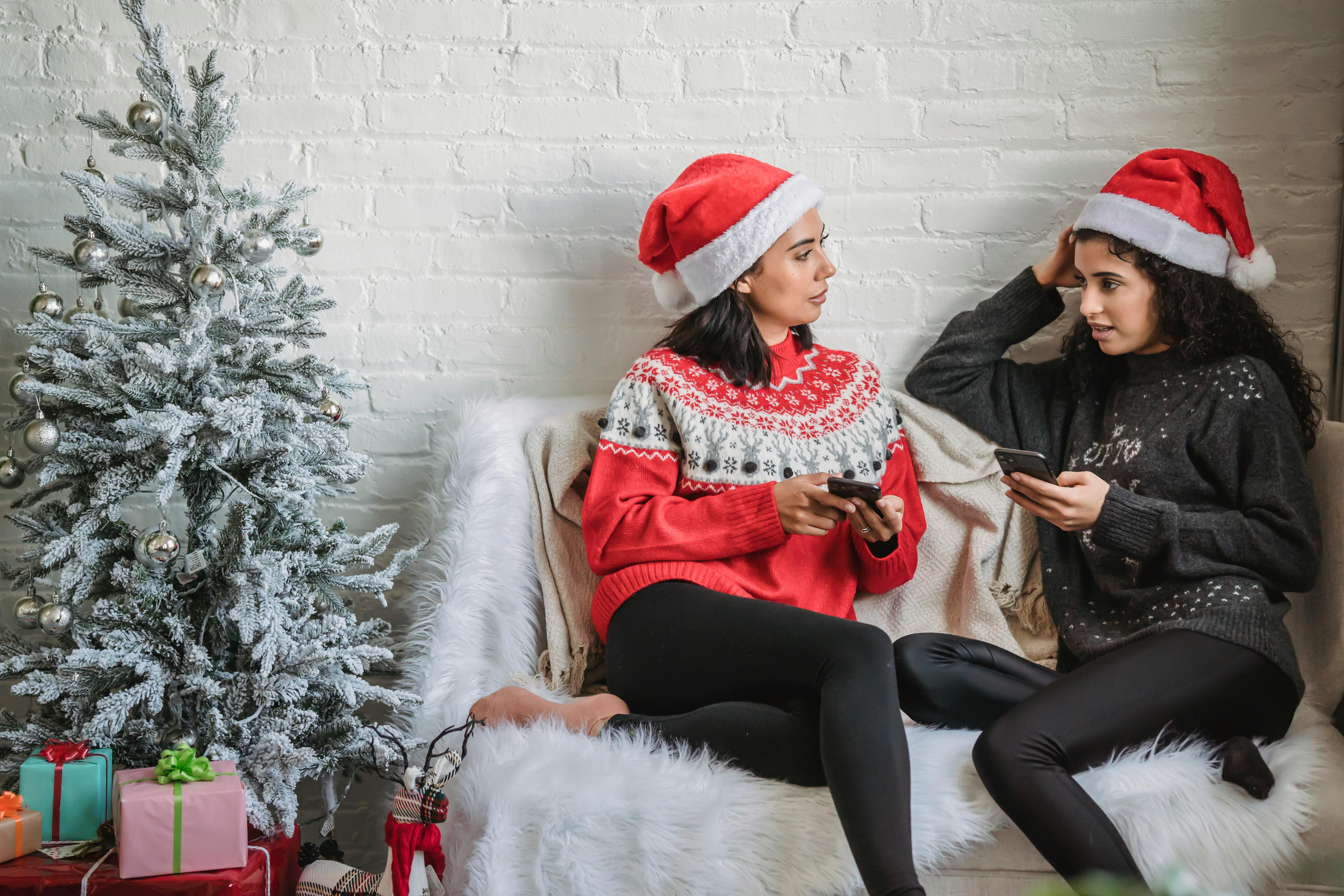 diverse women in santa hats with smartphone talking