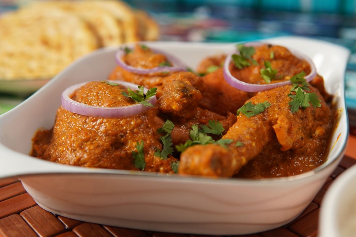 Pakistani-style chicken curry garnished with onions and coriander