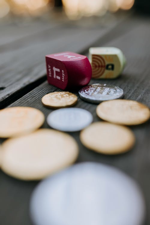 Close-Up Photo Of Dreidel Near Coins