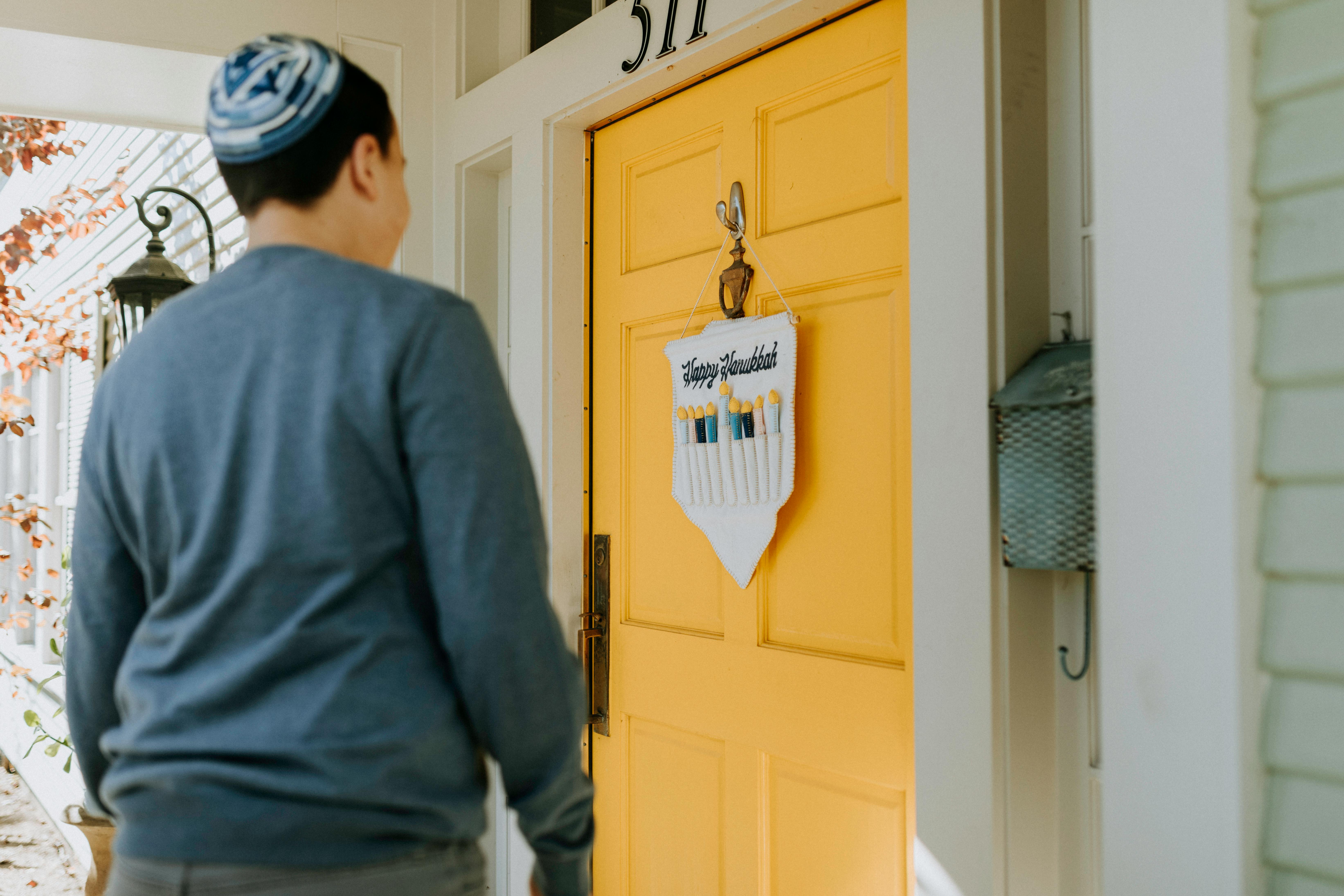 person in gray sweater standing near yellow wooden door