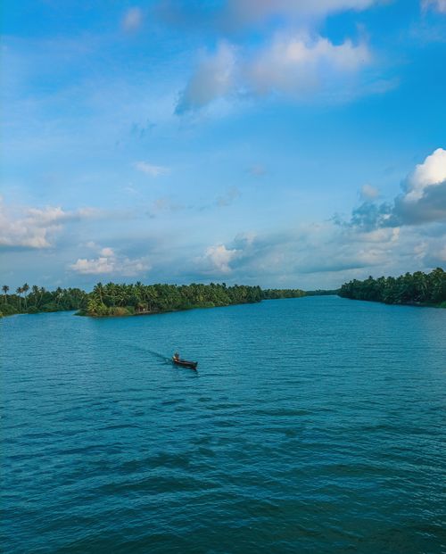 Free A stunning aerial view of a peaceful river in Kottayam, India, showcasing vibrant summer colors and a lone boat. Stock Photo