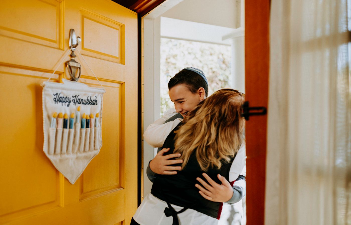 A mother and son share a warm hug during Hanukkah celebrations inside a home.