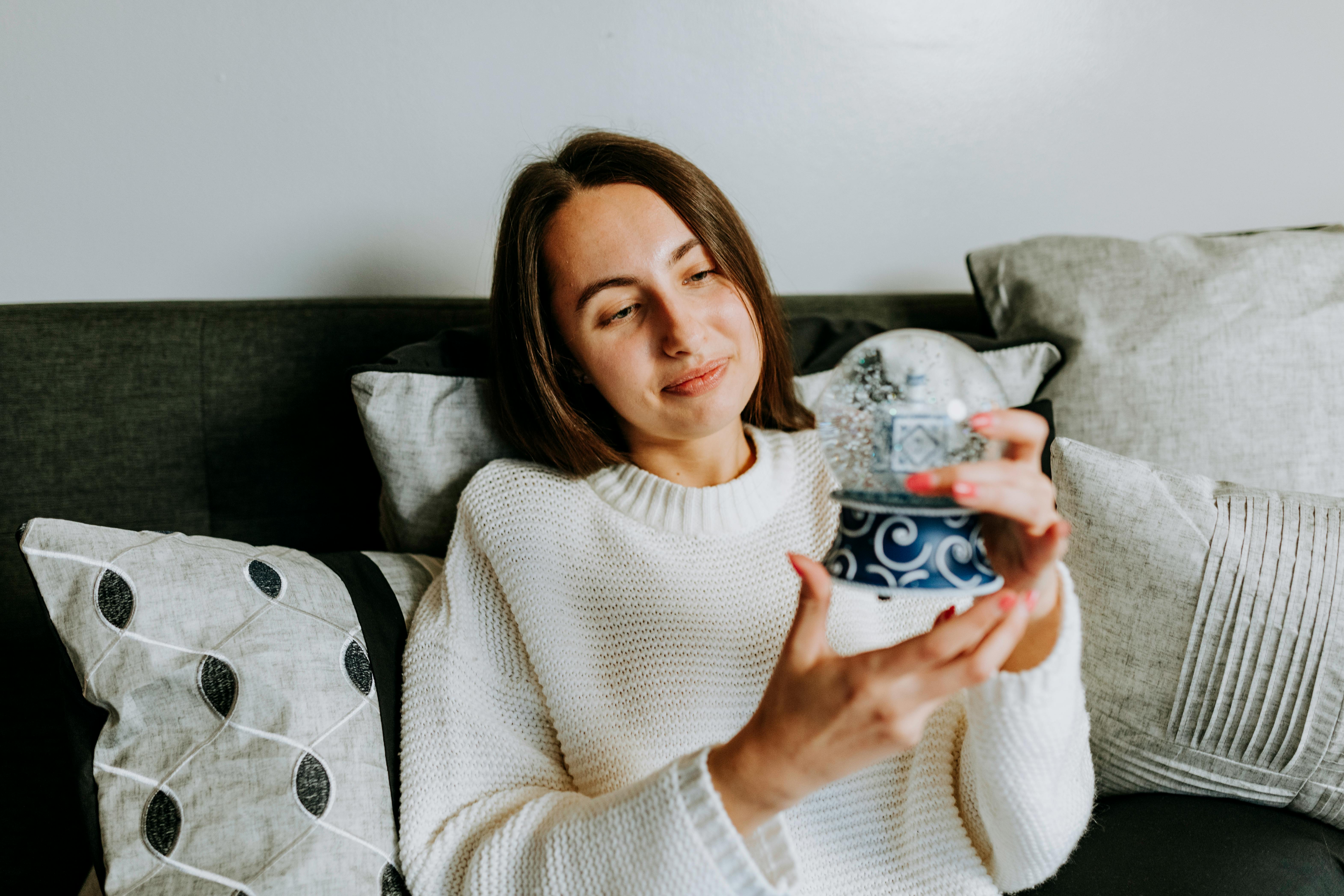 woman in white sweater holding a snow globe