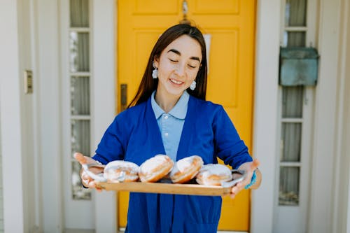 Photo Of Woman Holding A Wooden Tray Of Doughnuts