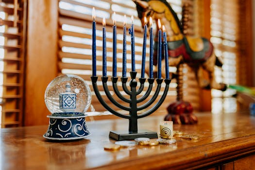 A festive Hanukkah scene with a menorah, snow globe, dreidel, and gelt on a wooden table.