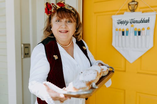 Photo Of Woman Carrying A Tray Of Fresh Doughnuts