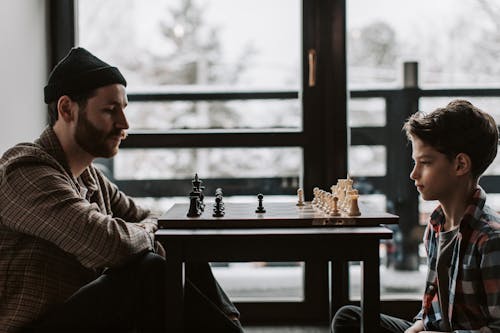 A Man and a Young Boy Playing Chessboard