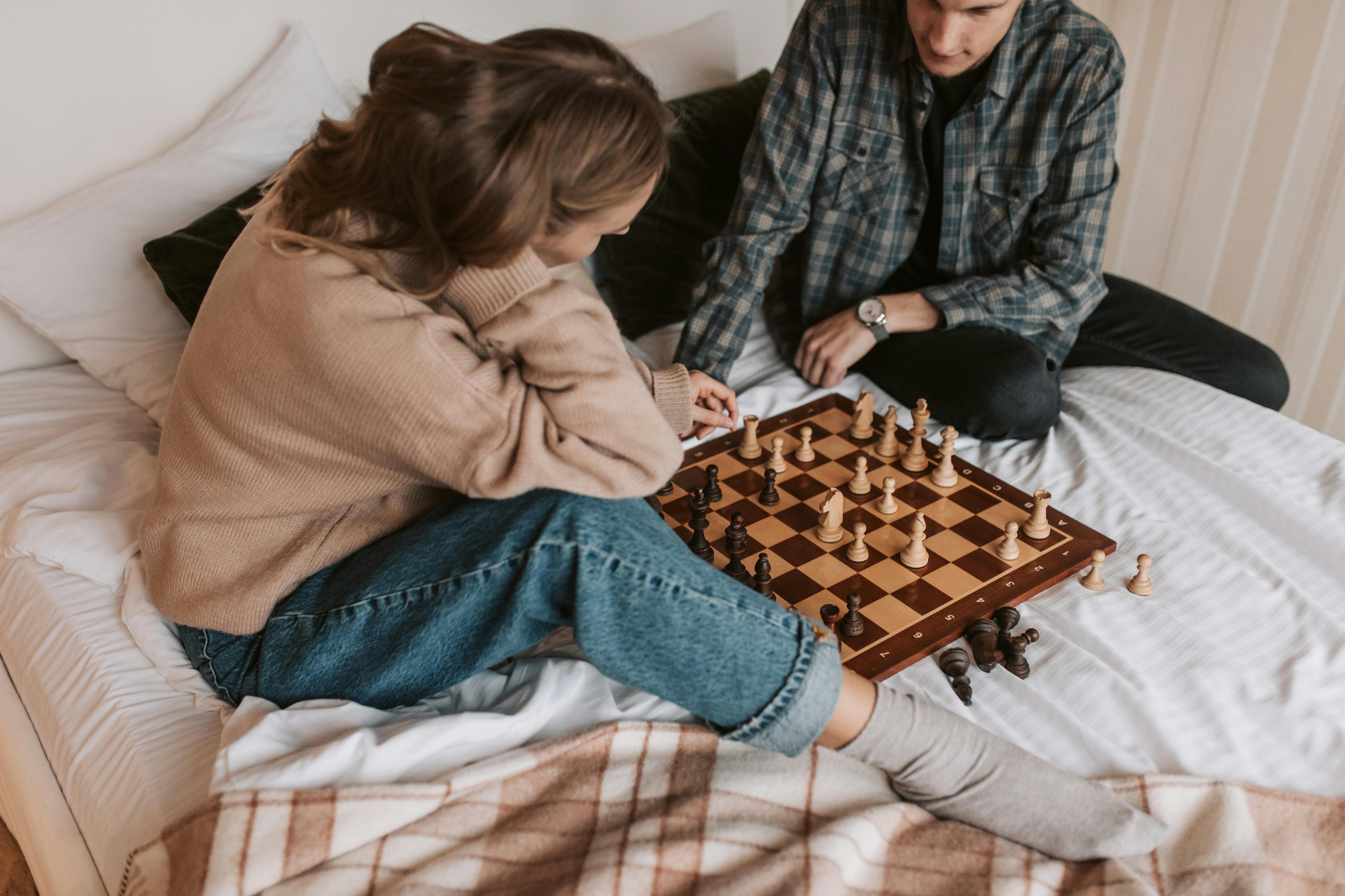 young couple playing chess while sitting at table at home - Unpacked