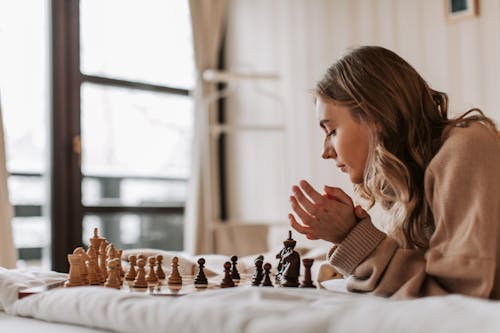 A Woman Playing Chess in Bed