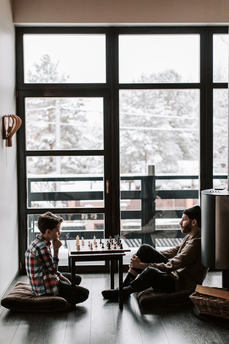 A Father And Son Playing A Game Of Chess At Home