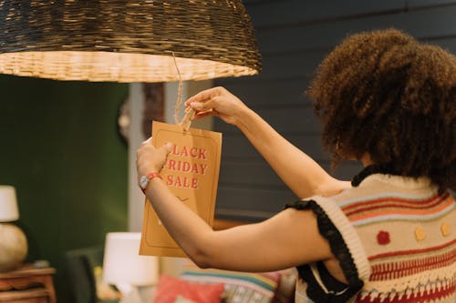 Free A Woman Hanging a Sale Sign on a Lamp Stock Photo