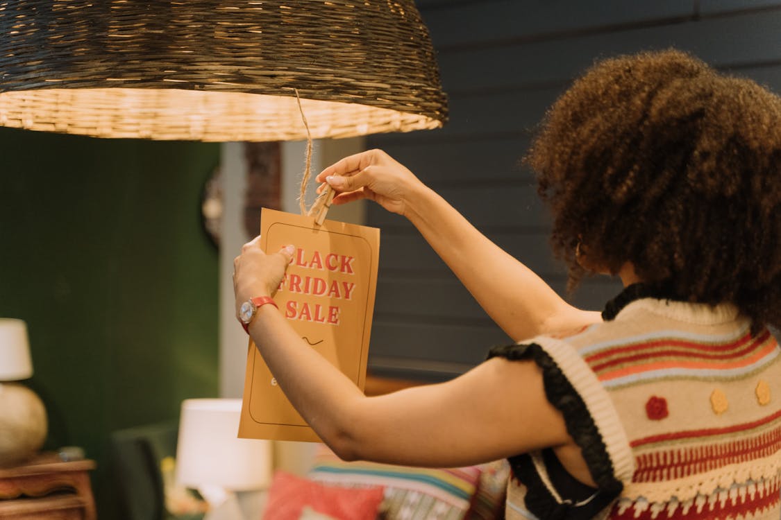 A Woman Hanging a Sale Sign on a Lamp