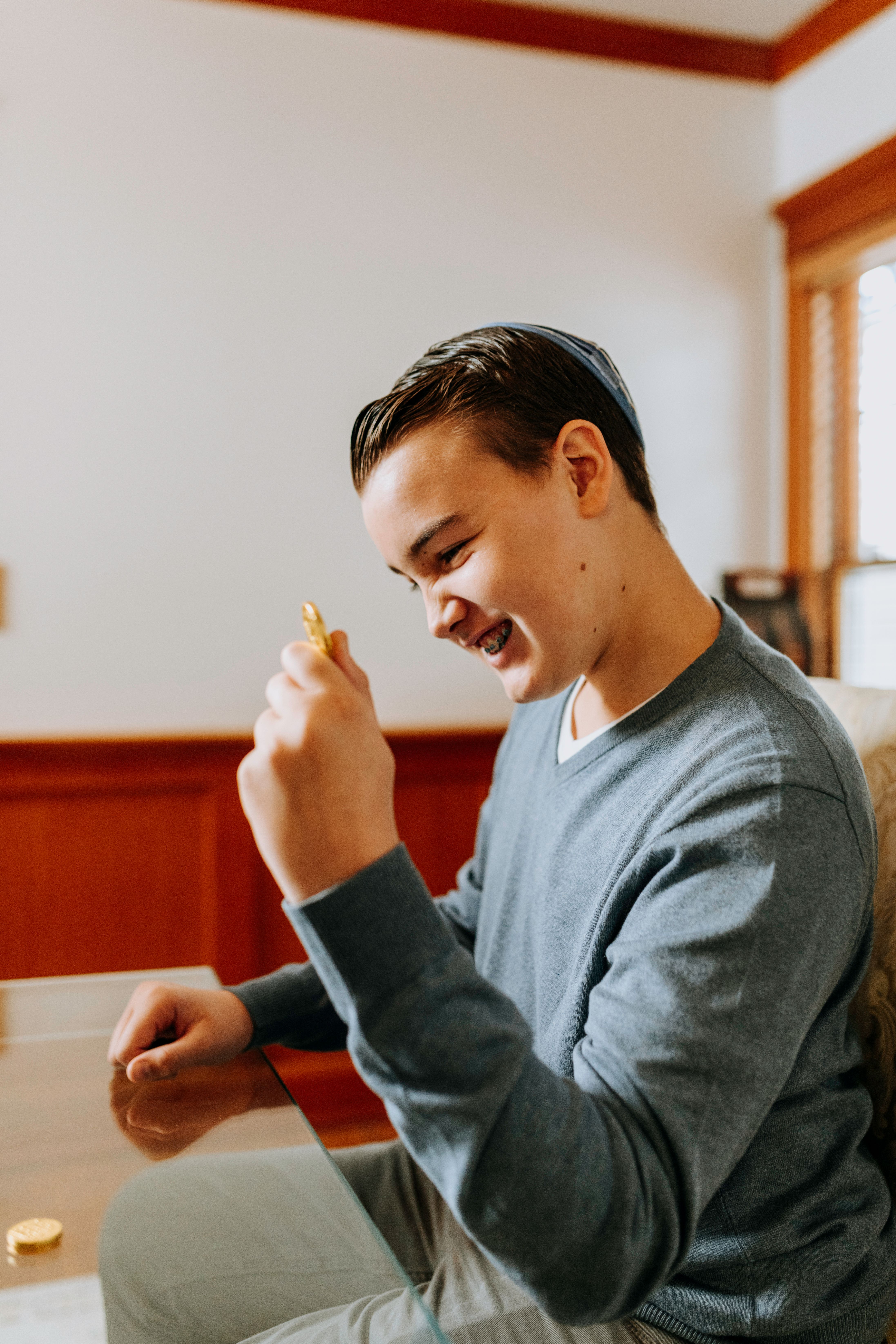 Young boy smiling while playing dreidel game during Hanukkah celebration indoors.