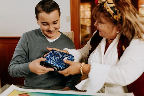 Photo Of Mother Handing Gift To Her Son 