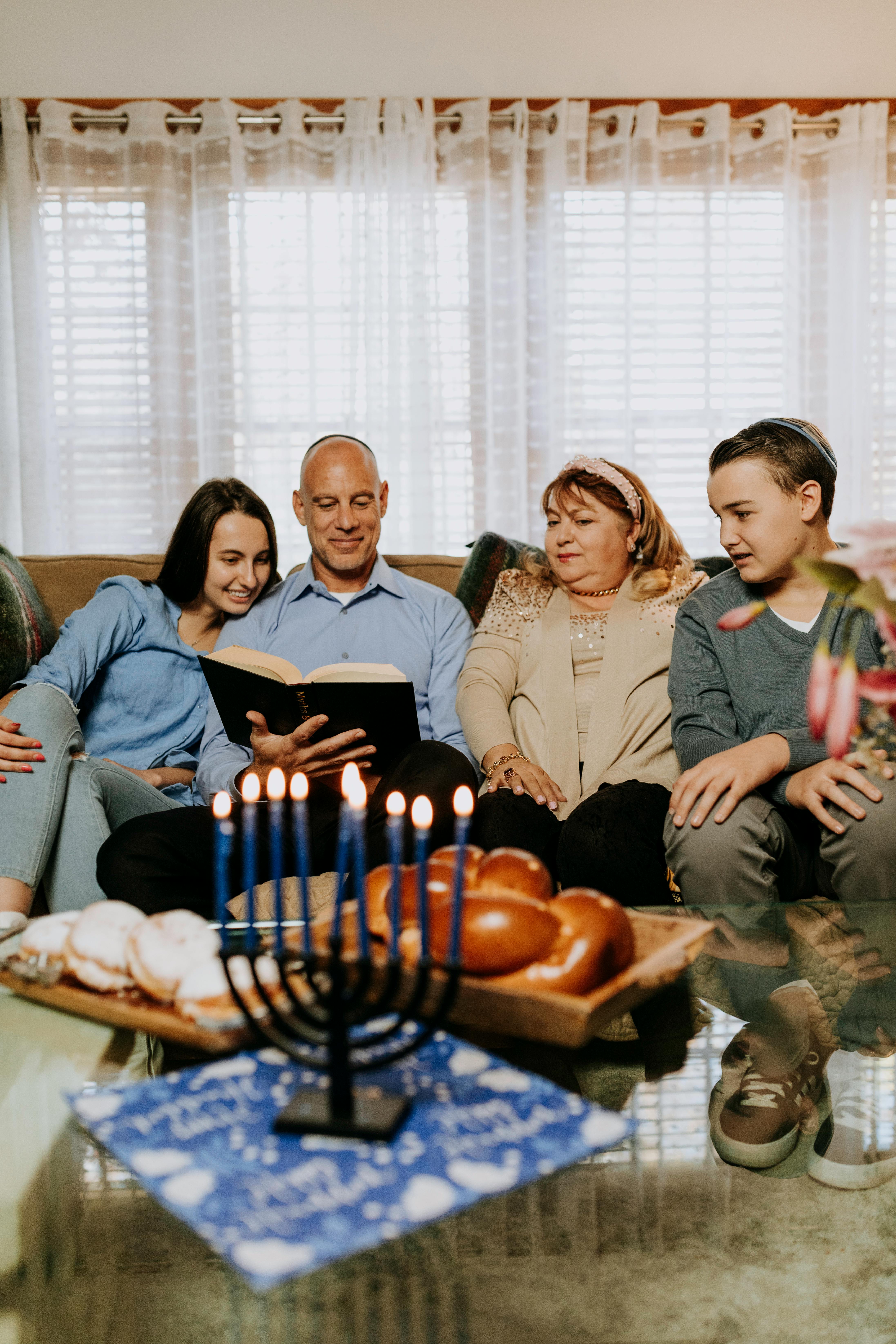A joyful family gathers indoors for Hanukkah, featuring menorah lighting and traditional foods.
