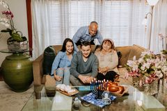 A joyful family celebrating Hanukkah with lit menorah, challah, and sufganiyot indoors.
