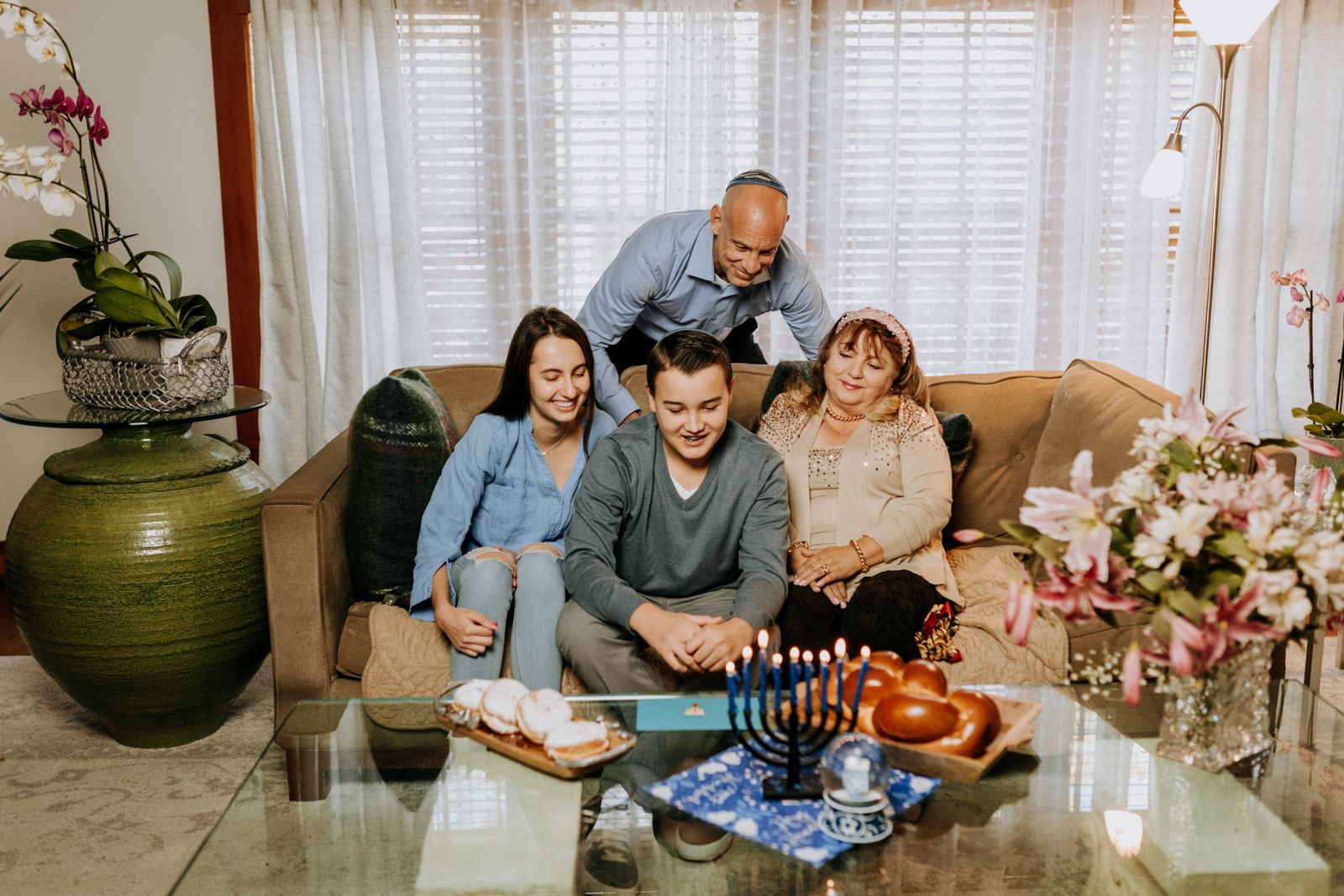 Three generations of a family on a sofa around a menorah and a challah