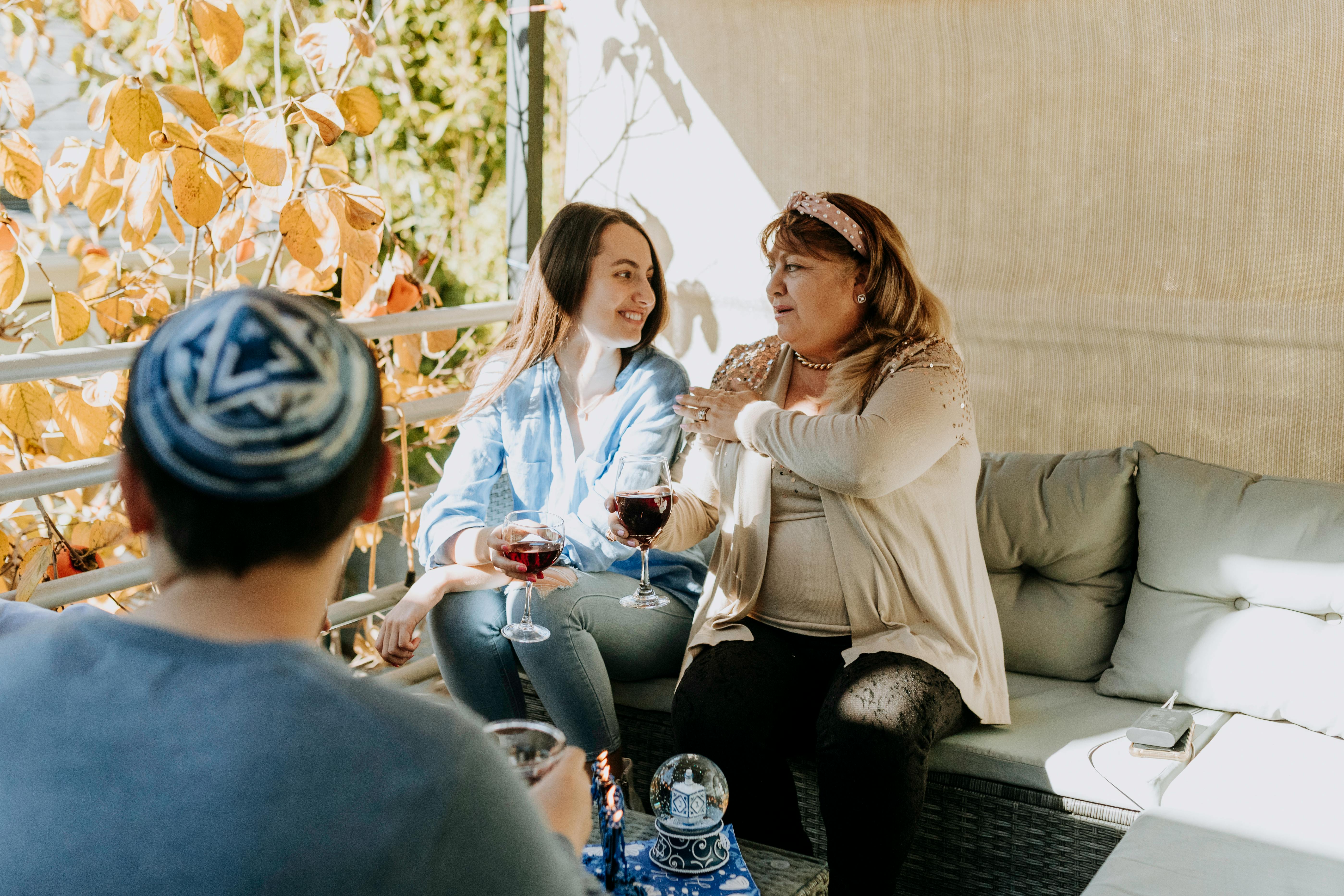 A family bonding over wine and conversation during a Hanukkah celebration indoors.