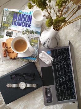 A stylish flat lay of a workspace featuring coffee, laptop, watch, and magazines.