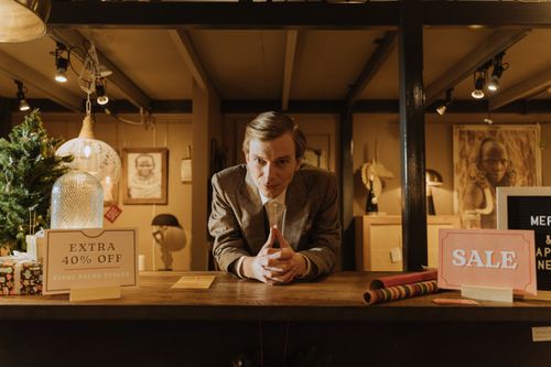 Free Salesman in a shop offering discounts and sales promotions with 40% off signs. Stock Photo