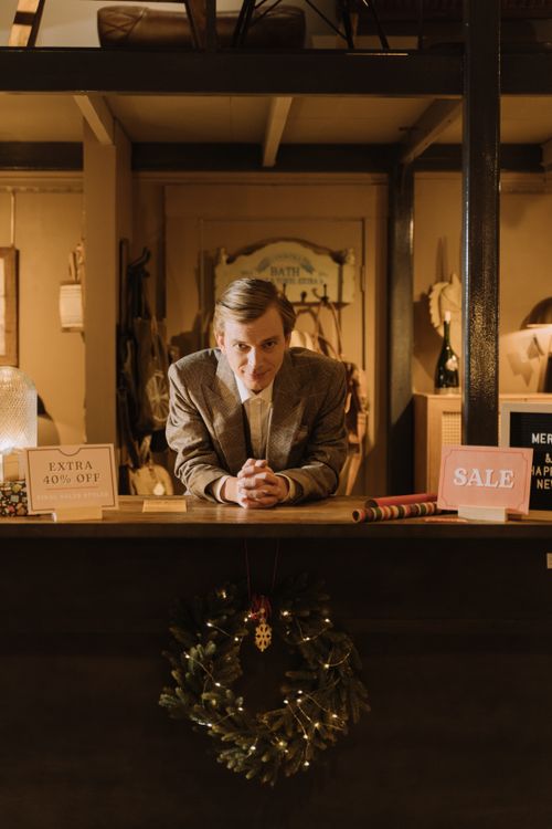 Free A salesman in a suit at a decorated shop counter with holiday sales signs. Stock Photo