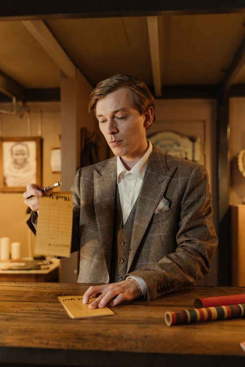 Free Gentleman in a classic suit writing receipts in a vintage shop interior. Stock Photo