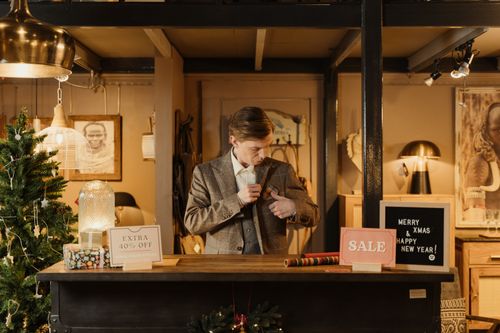 Free A salesman in a festive store setting, promoting a Christmas sale with seasonal decorations. Stock Photo
