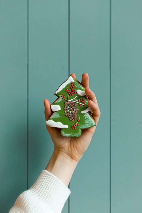 Free A close-up of a hand holding a handmade Christmas tree decoration with a blue panel background. Stock Photo