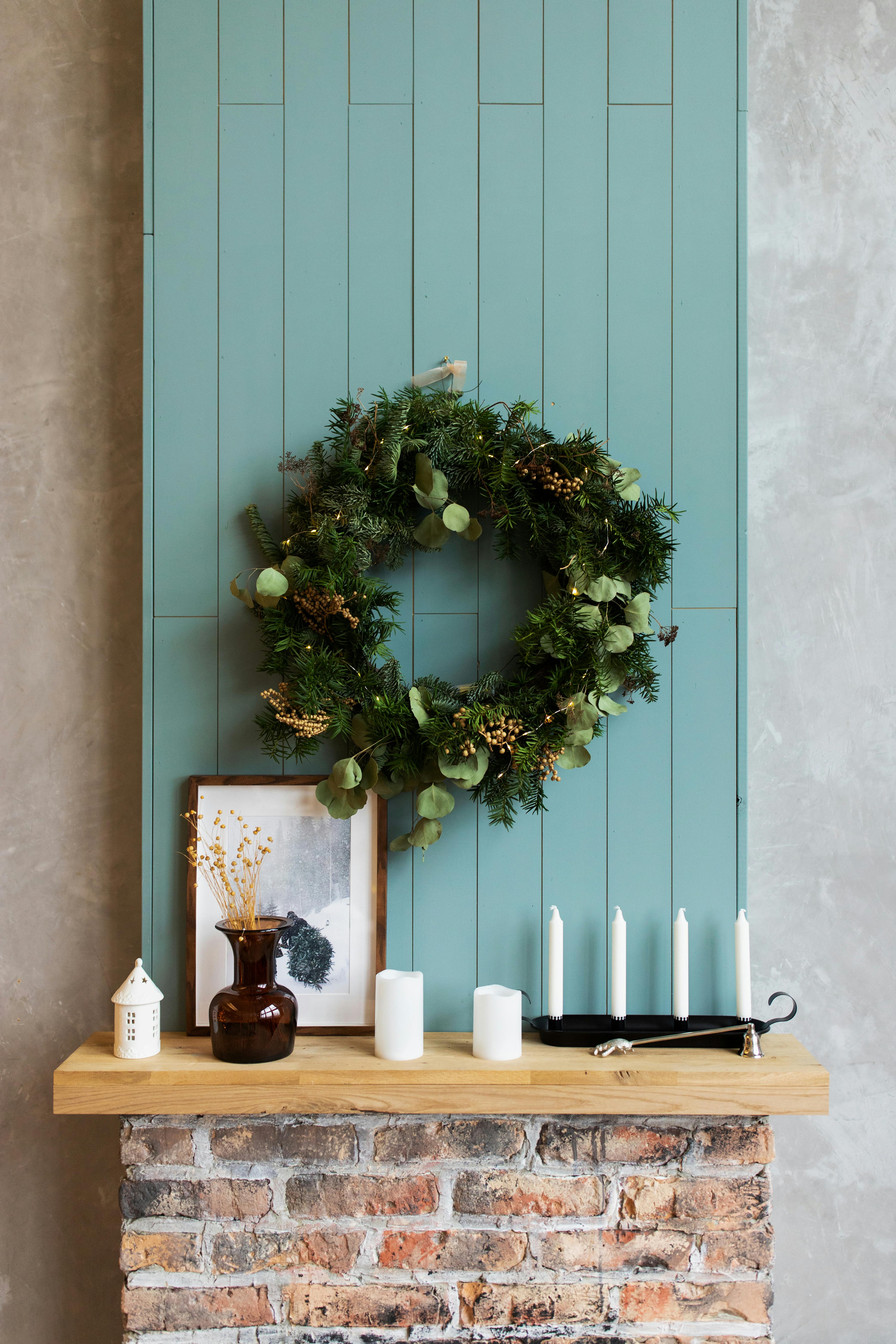 A cozy mantelpiece decorated with a wreath and candles, perfect for Christmas ambiance.
