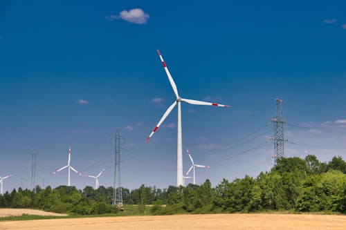 White and Red Wind Turbine on  Field Under Blue Sky