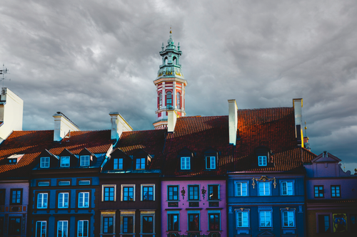 Free Dramatic view of colorful buildings and a historic tower in Warsaw, Poland under a moody sky. Stock Photo