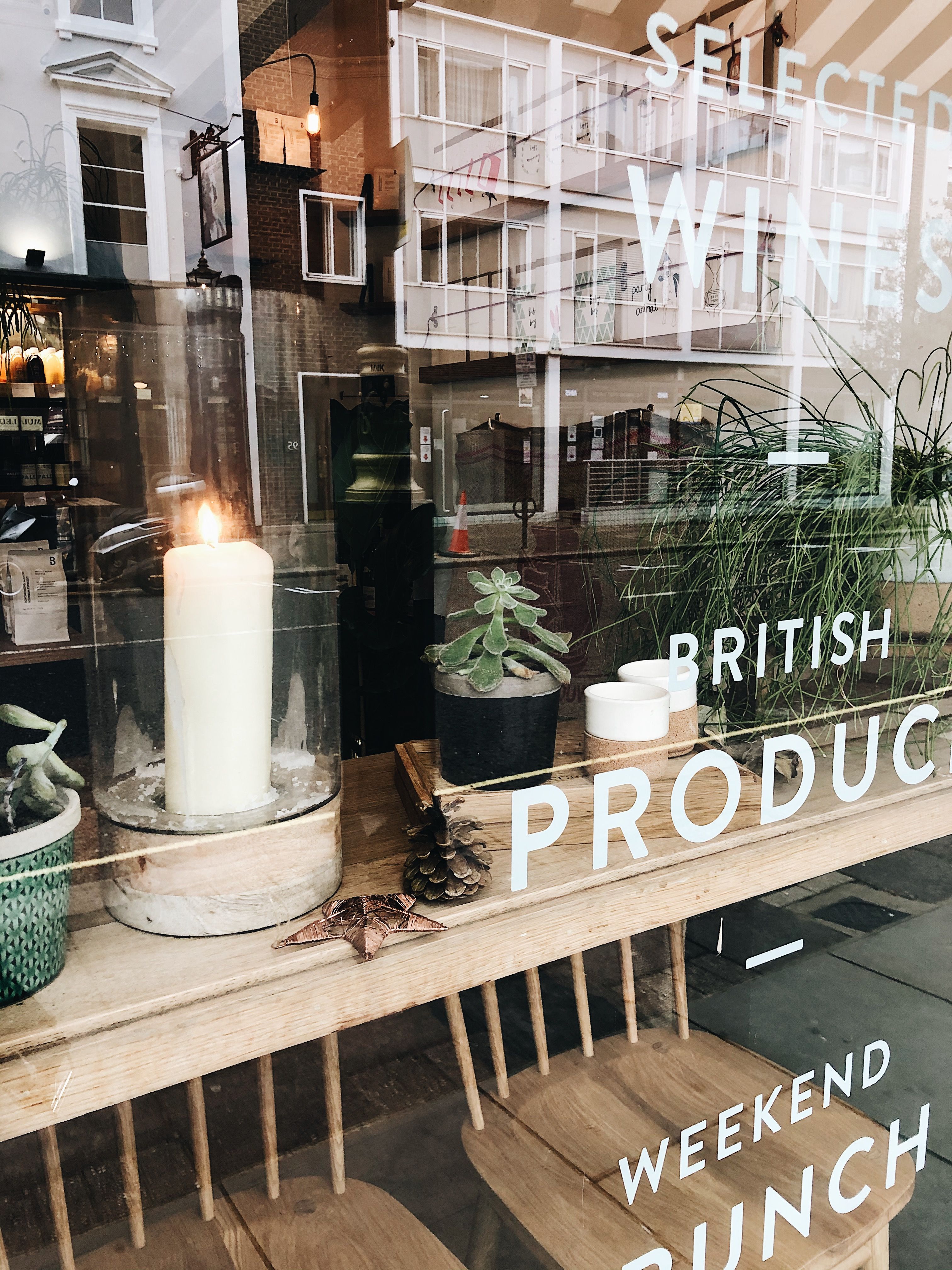 Warm candle-lit window display in a London café showcasing British products and décor.