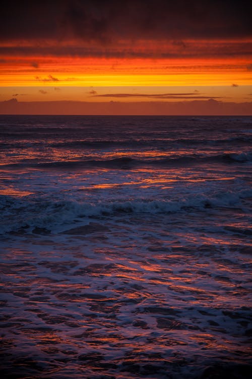 Free Ocean Waves Crashing the Beach Shore during Sunset Stock Photo