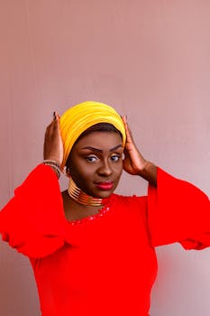 Elegant portrait of an African woman in red traditional attire with yellow headdress.
