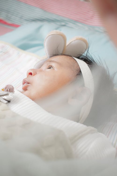 A Baby in White Shirt Lying on Bed