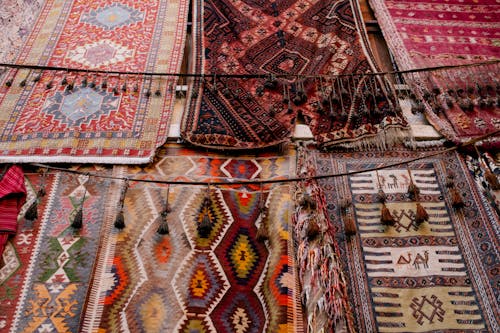 Free Colorful handmade weaved with oriental ornament middle east rugs hanging in open market Stock Photo